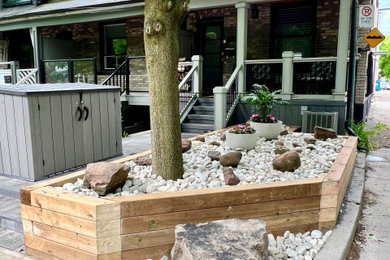 Photo of a mid-sized front yard river rock and wood fence flower bed in Toronto for summer.