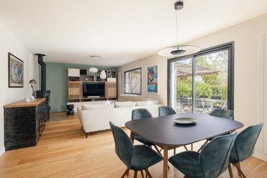 Réalisation d'une salle à manger ouverte sur le salon design de taille moyenne avec un mur blanc, parquet clair, un poêle à bois, un sol beige et éclairage.