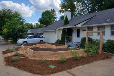 Design ideas for a mid-sized farmhouse full sun front yard mulch and wood fence landscaping in Portland for summer.