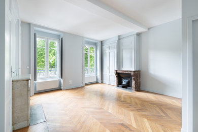 Aménagement d'un salon classique de taille moyenne, fermé et haussmannien avec un mur bleu, parquet clair, une cheminée standard et un sol marron.