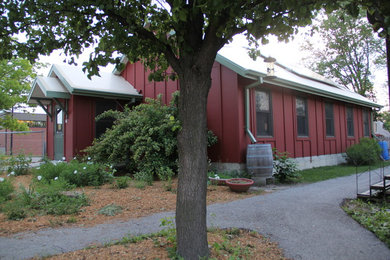 Foto della facciata di una casa rossa classica a un piano con tetto a capanna e rivestimento con lastre in cemento