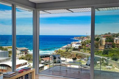 Inspiration for a mid-sized contemporary balcony in Sydney with a roof extension and glass railing.