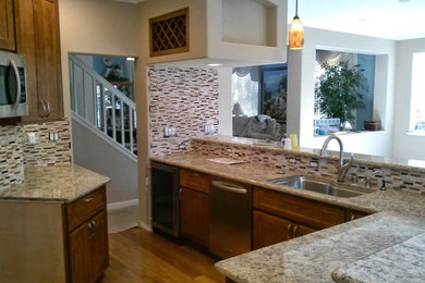 Inspiration for a cottage u-shaped dark wood floor and brown floor eat-in kitchen remodel in San Francisco with an undermount sink, louvered cabinets, brown cabinets, granite countertops, beige backsplash, glass tile backsplash, stainless steel appliances, no island and brown countertops