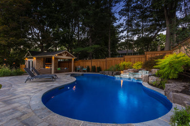 Inspiration for a mid-sized contemporary backyard pool in Toronto with natural stone pavers.