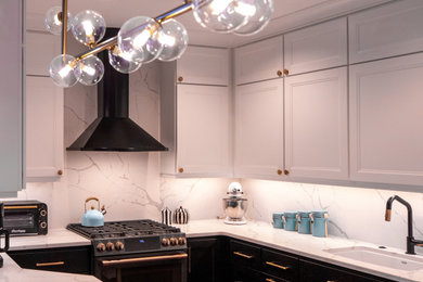 Transitional medium tone wood floor kitchen photo in Philadelphia with a single-bowl sink, black cabinets, quartz countertops, white backsplash, quartz backsplash, black appliances and white countertops