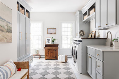 Example of a transitional galley white floor laundry room design in Boston with an undermount sink, recessed-panel cabinets, gray cabinets, white walls, a side-by-side washer/dryer and white countertops