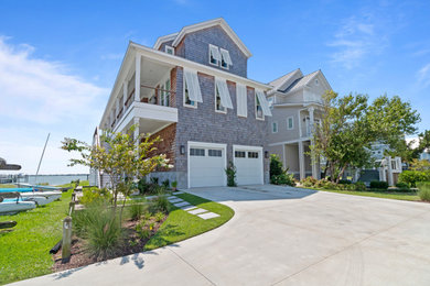 Large beach style brown three-story wood and shingle exterior home photo in Raleigh with a metal roof and a gray roof