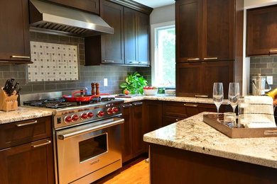 Open concept kitchen - mid-sized transitional l-shaped light wood floor and beige floor open concept kitchen idea in Orlando with an undermount sink, shaker cabinets, dark wood cabinets, granite countertops, gray backsplash, ceramic backsplash, stainless steel appliances and an island