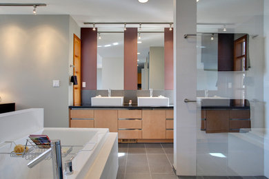 Bathroom - large modern master gray tile and porcelain tile porcelain tile and gray floor bathroom idea in Calgary with flat-panel cabinets, light wood cabinets, gray walls, a vessel sink and solid surface countertops