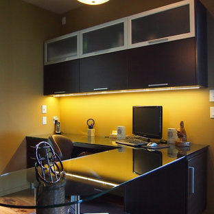 This is an example of a medium sized modern home office and library in Grand Rapids with medium hardwood flooring, a built-in desk and green walls.