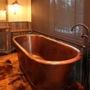 Inspiration pour une grande salle de bain principale chalet avec un lavabo encastré, des portes de placard en bois brun, une baignoire indépendante, un mur beige, un sol en bois brun, un placard à porte shaker et un plan de toilette en cuivre.