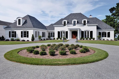 Large traditional two-storey brick white house exterior in Other with a hip roof and a shingle roof.