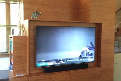 Photo of a large contemporary open concept home theatre in San Francisco with beige walls, medium hardwood floors, a wall-mounted tv and brown floor.