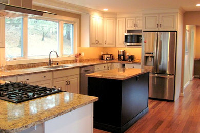 This is an example of a mid-sized traditional u-shaped separate kitchen in Boston with an undermount sink, raised-panel cabinets, white cabinets, granite benchtops, stainless steel appliances, medium hardwood floors, with island, brown floor and brown benchtop.