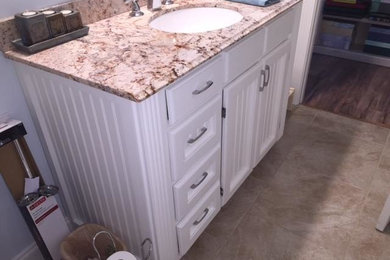 Inspiration for a mid-sized timeless 3/4 beige floor and ceramic tile bathroom remodel in New Orleans with recessed-panel cabinets, white cabinets, a two-piece toilet, blue walls, an undermount sink and granite countertops