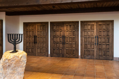 ロサンゼルスにあるラグジュアリーな広いトラディショナルスタイルのおしゃれな玄関ドア (白い壁、テラコッタタイルの床、茶色いドア、オレンジの床、表し梁) の写真