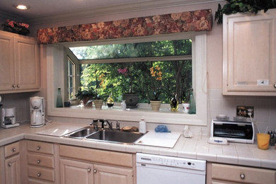 Inspiration for a timeless kitchen remodel in Chicago with a double-bowl sink, raised-panel cabinets, light wood cabinets, tile countertops, beige backsplash, ceramic backsplash and white appliances