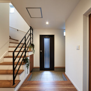 他の地域の片開きドアモダンスタイルのおしゃれな玄関ホール (白い壁、濃色木目調のドア) の写真