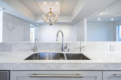 Open concept kitchen - large modern galley medium tone wood floor and brown floor open concept kitchen idea in Houston with an undermount sink, shaker cabinets, white cabinets, marble countertops, gray backsplash, marble backsplash, stainless steel appliances, an island and gray countertops