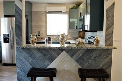 Example of a mid-sized minimalist l-shaped ceramic tile and gray floor eat-in kitchen design in Tampa with a double-bowl sink, flat-panel cabinets, turquoise cabinets, granite countertops, gray backsplash, ceramic backsplash, stainless steel appliances, a peninsula and gray countertops