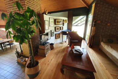 Foto de salón abierto bohemio de tamaño medio con paredes negras, suelo de madera clara, chimenea de doble cara, marco de chimenea de ladrillo y papel pintado