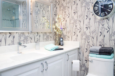 Inspiration for a small modern corner shower remodel in Toronto with a drop-in sink, recessed-panel cabinets, white cabinets, multicolored walls, a one-piece toilet and solid surface countertops