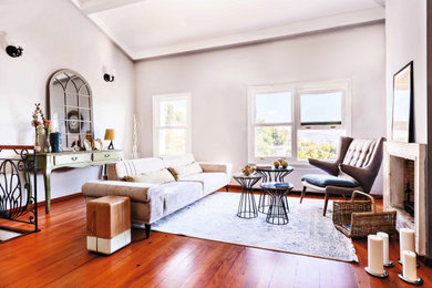 Example of a mid-sized trendy open concept light wood floor and brown floor living room design in London with gray walls, a standard fireplace, a stone fireplace and no tv