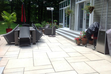 Inspiration for a mid-sized backyard patio in Montreal with natural stone pavers.