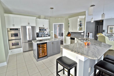 Mid-sized trendy kitchen photo in Toronto with flat-panel cabinets, white cabinets, quartz countertops, gray backsplash, stone tile backsplash and two islands