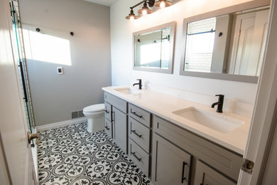 This is an example of a medium sized traditional ensuite bathroom in Detroit with shaker cabinets, grey cabinets, a two-piece toilet, ceramic flooring, a submerged sink, quartz worktops, black floors, white worktops, double sinks and a freestanding vanity unit.