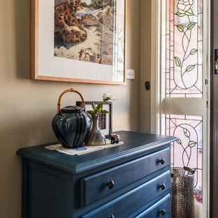 Cette photo montre une petite entrée éclectique avec un couloir, un mur vert, un sol en bois foncé, une porte simple et une porte blanche.