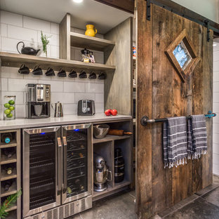 Idée de décoration pour une grande arrière-cuisine linéaire bohème avec un plan de travail en quartz modifié, une crédence blanche, une crédence en carreau de porcelaine, un électroménager en acier inoxydable, un sol gris, un plan de travail blanc, un placard sans porte, des portes de placard grises et béton au sol.