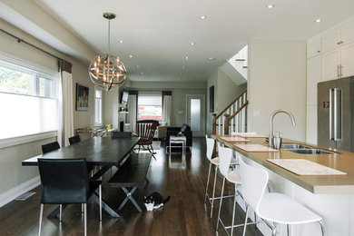 Trendy single-wall medium tone wood floor eat-in kitchen photo in Toronto with a double-bowl sink, shaker cabinets, white cabinets, gray backsplash and stainless steel appliances