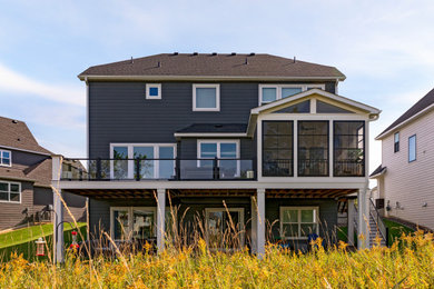 Exemple d'un porche d'entrée de maison arrière avec une moustiquaire, une extension de toiture et un garde-corps en verre.