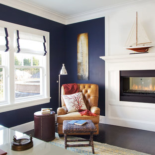 Imagen de despacho marinero, grande, con paredes azules, suelo de madera oscura, chimenea de doble cara, marco de chimenea de madera y escritorio independiente