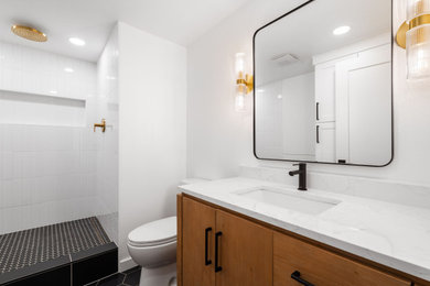 Example of a mid-sized trendy white tile and subway tile ceramic tile, black floor and single-sink doorless shower design in Portland with flat-panel cabinets, medium tone wood cabinets, an undermount sink, quartzite countertops, a niche and a built-in vanity
