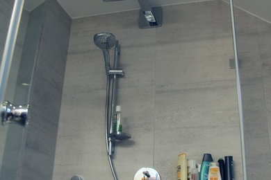 Mittelgroßes Modernes Badezimmer mit Einbaubadewanne, Duschbadewanne, Wandtoilette, grauen Fliesen, Porzellanfliesen, weißer Wandfarbe, Porzellan-Bodenfliesen, grauem Boden und Falttür-Duschabtrennung in München