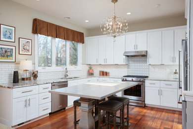Transitional u-shaped kitchen in DC Metro with an undermount sink, shaker cabinets, white cabinets, white splashback, stainless steel appliances, medium hardwood floors, with island, brown floor and grey benchtop.