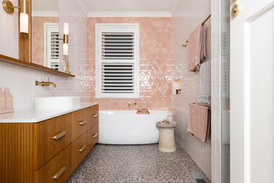 Photo of a large contemporary master bathroom in Melbourne with medium wood cabinets, a freestanding tub, an alcove shower, a one-piece toilet, ceramic tile, a vessel sink, engineered quartz benchtops, multi-coloured floor, a hinged shower door, white benchtops, a niche, a single vanity, a floating vanity, furniture-like cabinets, pink tile, white walls and terrazzo floors.