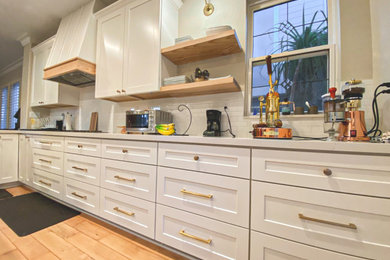 Example of a large 1960s l-shaped light wood floor and multicolored floor enclosed kitchen design in San Diego with an undermount sink, shaker cabinets, white cabinets, quartz countertops, white backsplash, porcelain backsplash, stainless steel appliances, an island and white countertops