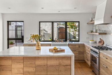 Example of a large eclectic u-shaped medium tone wood floor and brown floor eat-in kitchen design in San Diego with a farmhouse sink, flat-panel cabinets, light wood cabinets, quartzite countertops, multicolored backsplash, stone slab backsplash, paneled appliances, an island and multicolored countertops