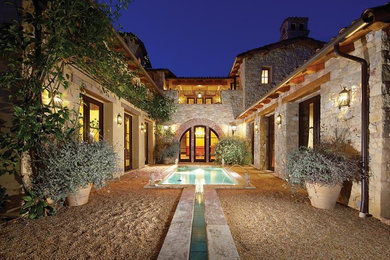 Mid-sized mediterranean gray two-story stone exterior home idea in Orange County with a tile roof