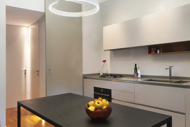 Foto di una cucina abitabile contemporanea con lavello da incasso, ante lisce e parquet chiaro