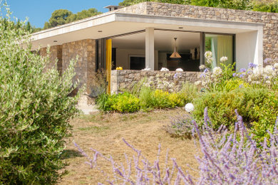 Réalisation d'une façade de maison design en pierre de plain-pied.
