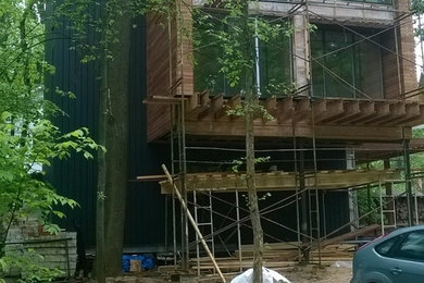 Foto de fachada de casa marrón actual grande de tres plantas con revestimiento de madera, tejado plano y tejado de varios materiales