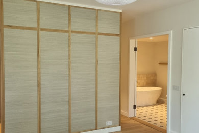 Photo of a large modern master bedroom in London with beige walls and plywood flooring.