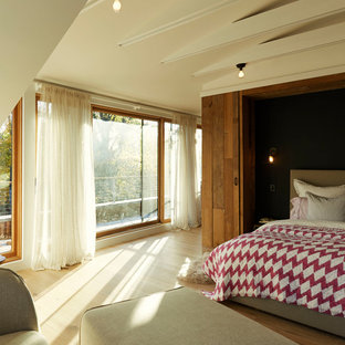 Foto di una camera matrimoniale etnica con pareti beige, pavimento in legno massello medio e pavimento beige