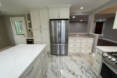 Example of a huge transitional multicolored floor and porcelain tile eat-in kitchen design in Chicago with white cabinets, quartz countertops, beige backsplash, stainless steel appliances, white countertops, recessed-panel cabinets, subway tile backsplash, a peninsula and an undermount sink