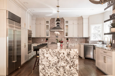 Large elegant u-shaped medium tone wood floor and brown floor eat-in kitchen photo in Atlanta with a farmhouse sink, shaker cabinets, beige cabinets, granite countertops, metallic backsplash, stainless steel appliances, an island and multicolored countertops