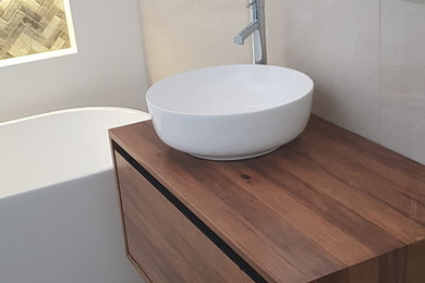 Photo of a mid-sized modern master bathroom in Sydney with medium wood cabinets, a freestanding tub, beige walls and beige floor.